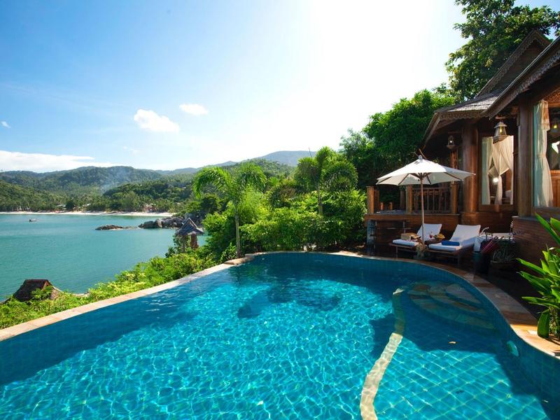 Pool mit Blick auf See und Berge neben einem Holzferienhaus.
