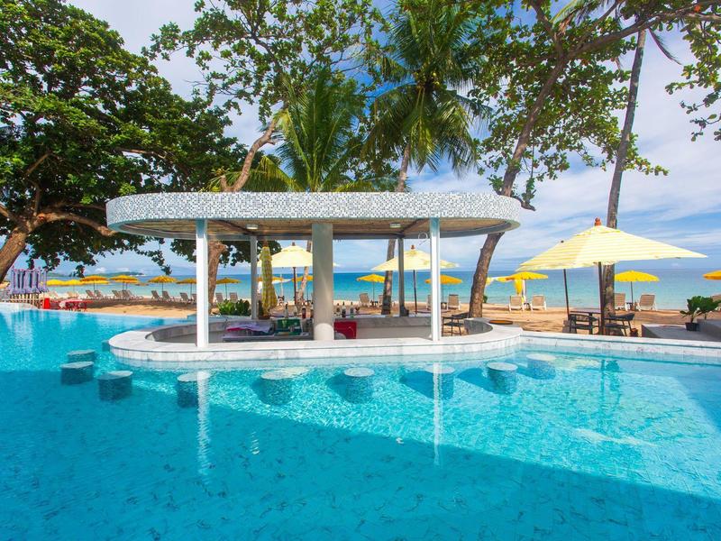 Großer Pool mit blauem Wasser, Swim-up-Bar, Sonnenschirmen und Palmen im tropischen Garten.