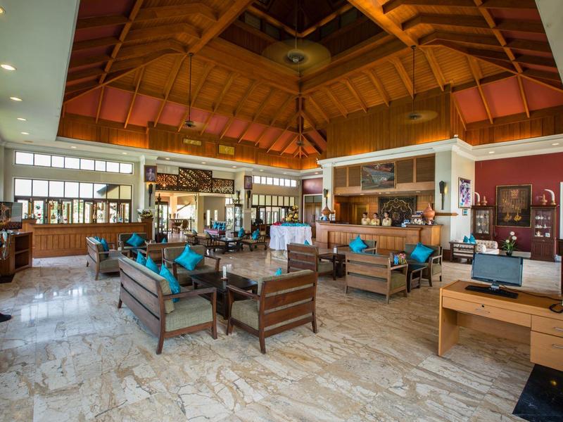 Großer Wohnraum mit Holzmöbeln, Marmorfußboden und hoher, holzverkleideter Decke.