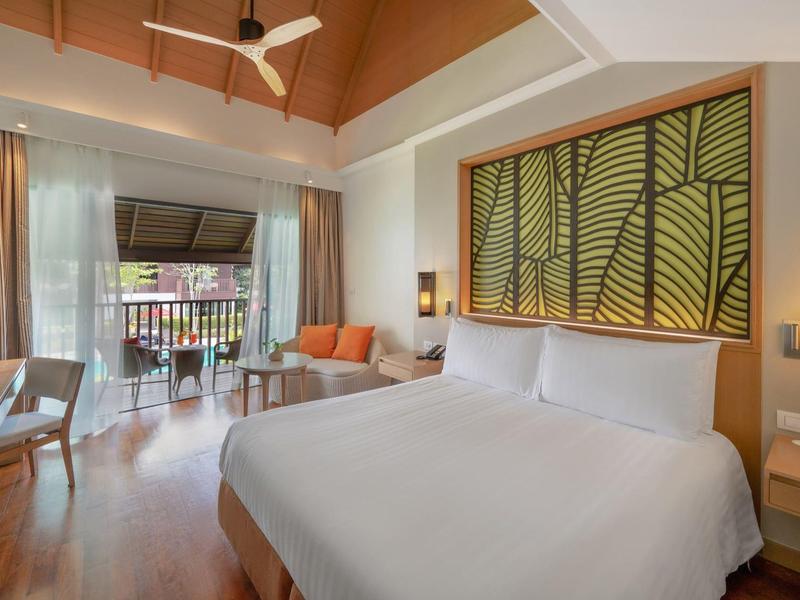 Helles Schlafzimmer mit großem Bett, Holzdecke, Terrassentüren und warmer Einrichtung.