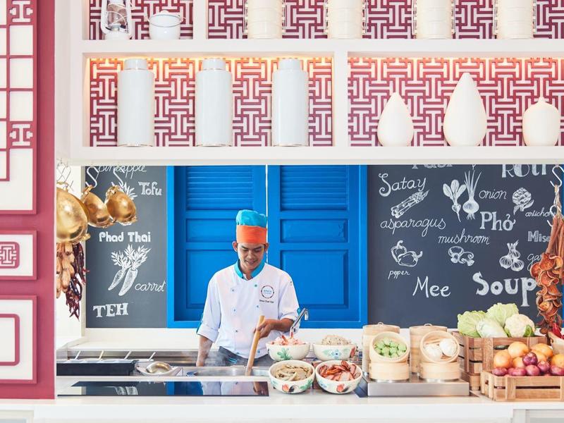 Ein Mann kocht in einer bunten Marktküche mit spezialisierten und frischen Zutaten.