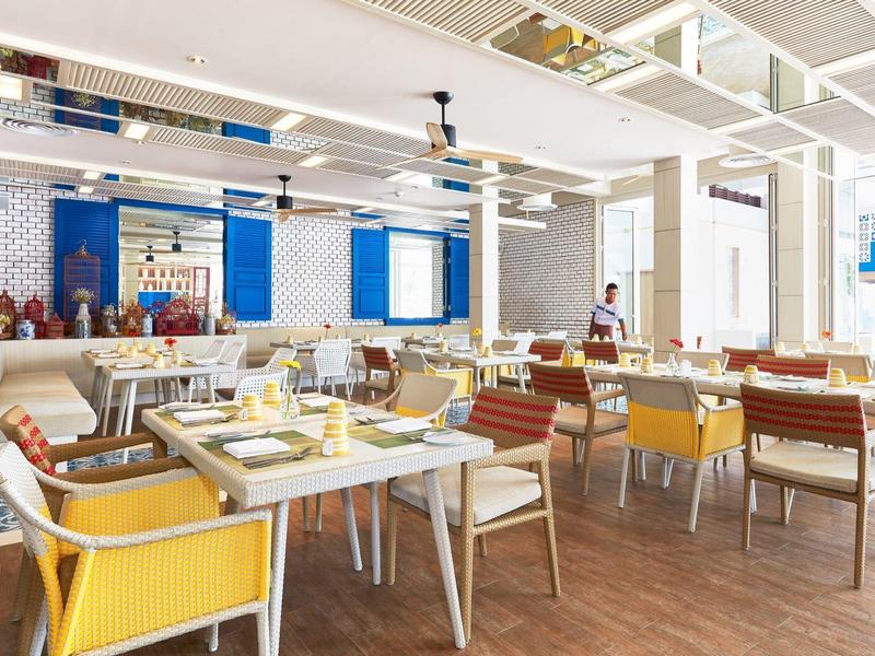 Modernes Restaurant mit bunten Stühlen, Holztischen und großem Fenster für viel Tageslicht.