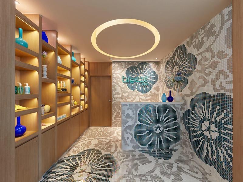 Moderner Spa-Raum mit Holzregalen, blauen Dekorationsgegenständen und floralen Wandfliesen.