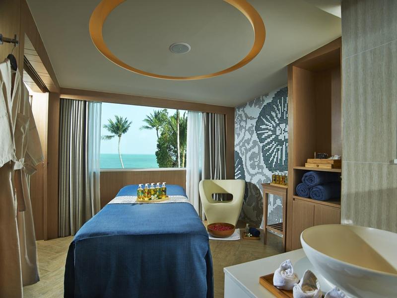 Modernes Zimmer mit blauem Bett, Meerblick, Holzregalen und sonnendurchflutetem Balkon.