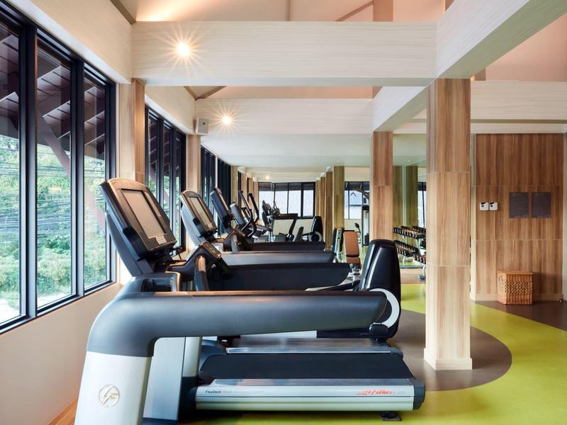 Modernes Fitnessstudio mit Laufbändern, großen Fenstern und warmen Holzakzenten.