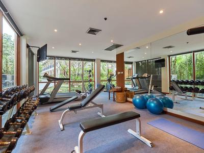 Helles Fitnessstudio mit Hanteln, Laufbändern, Bänken, Gymnastikbällen und großen Fenstern.