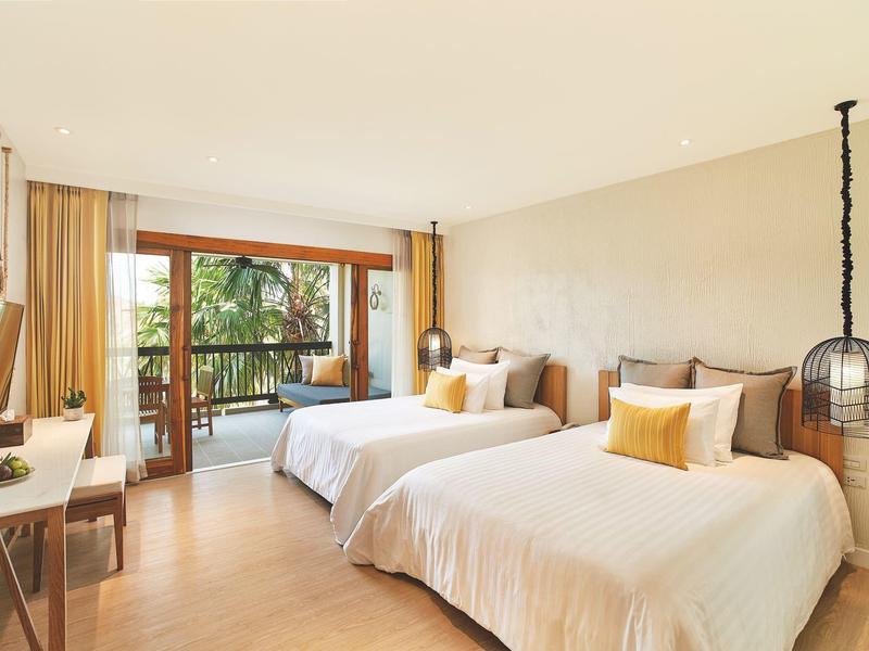 Helles Hotelzimmer mit zwei Betten, Balkon und natürlichem Licht.