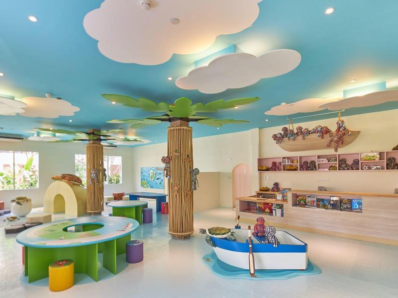 Heller und bunter Kinderspielbereich mit Schiff, Bauelementen und Wolkendecke im Hotel