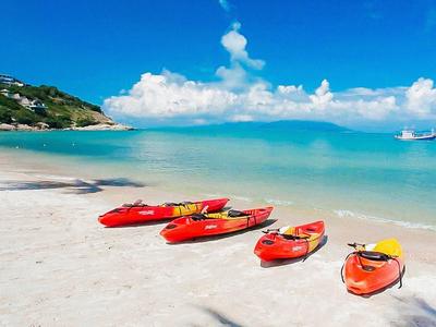 Červené kajaky na bílé písečné pláži s tyrkysovým mořem a modrou oblohou