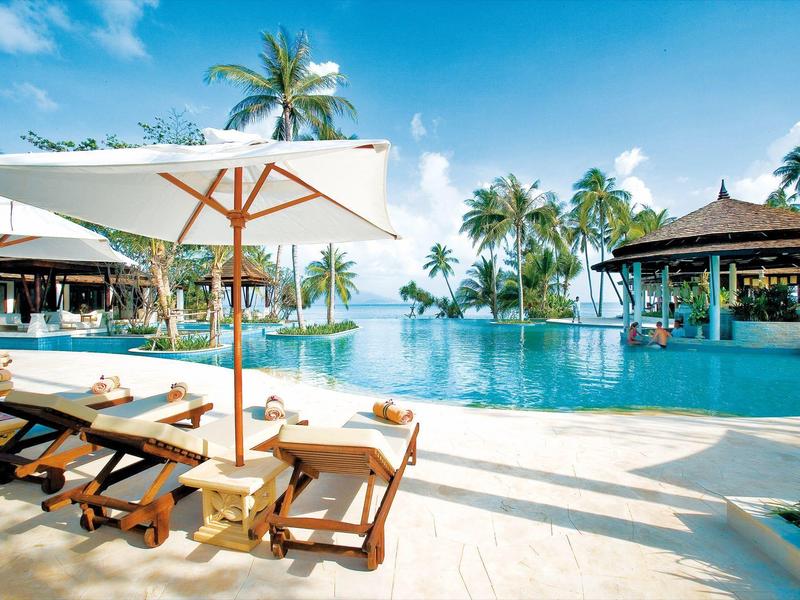 Luxusní bazénová oblast s lehátky, slunečníky a palmami v tropickém resortu