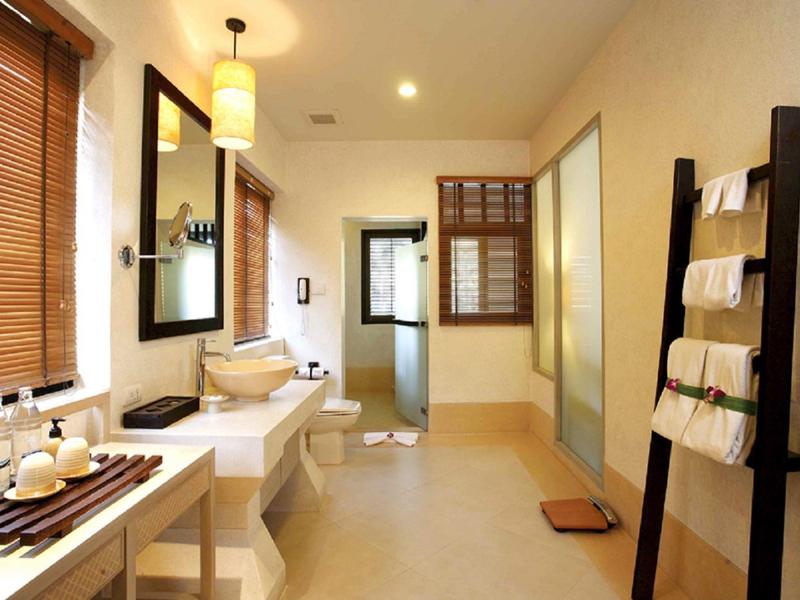 Světla, čistá koupelna s dřevěnými doplňky, velkým zrcadlem a žebříkem na ručníky.