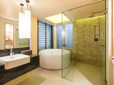 Modernes Badezimmer mit rundem Whirlpool, Glasdusche, Waschbecken und sanfter Beleuchtung.