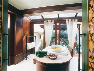 Elegantes Badezimmer mit ovaler Badewanne, Holzverkleidung und großen Fenstern mit weißen Vorhängen.