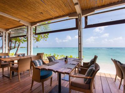 Open dining area with wooden floor and sea view under clear sky.