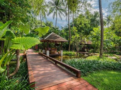 Wooden walkway in a tropical garden with palm trees and green plants