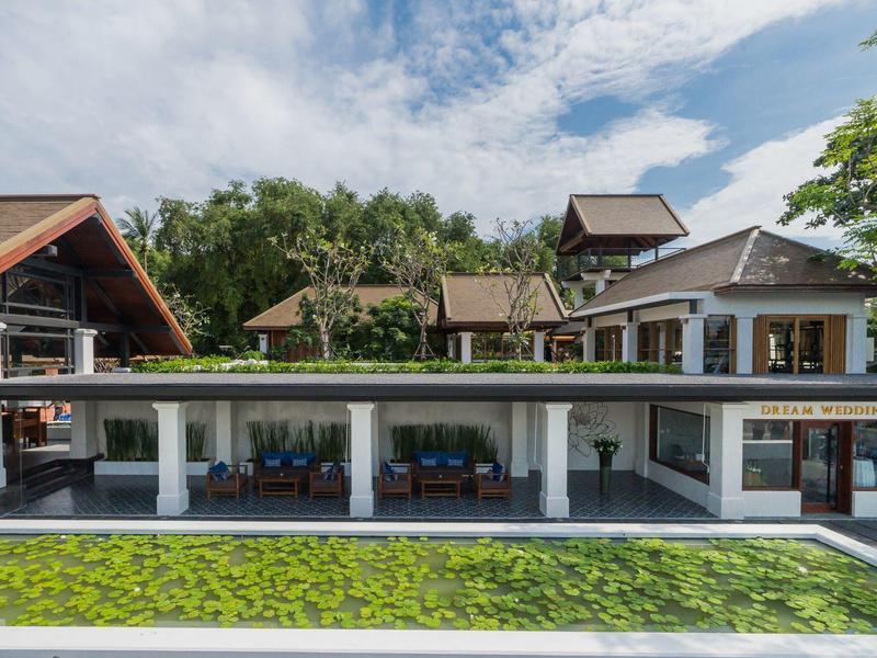 Modernes Haus mit großen Glasfenstern, Gartenteich, Bäumen und blauem Himmel im Hintergrund.