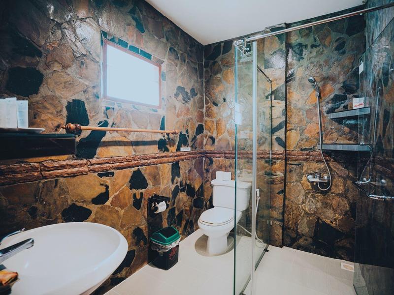 Moderne Badezimmer mit dunkel gemusterten Fliesen, weißem WC, Waschbecken und Glasdusche.