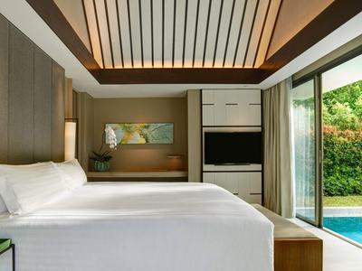 Nowoczesna sypialnia z dużym łóżkiem, drewnianymi akcentami i widokiem na basen i ogród.