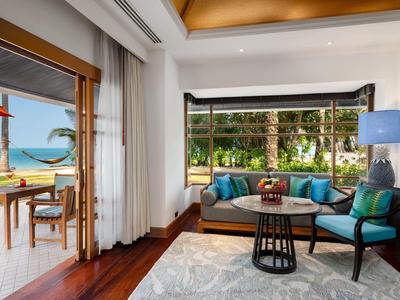 Jasny salon z sofami, dywanem i widokiem na taras i morze.