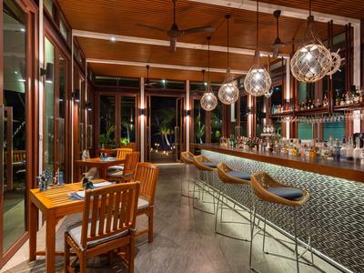 Nowoczesna restauracja hotelowa z barem, drewnianymi stołami, krzesłami i wiszącymi kulistymi lampami.