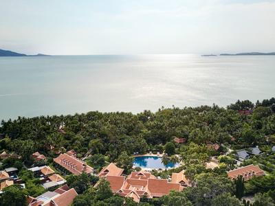 Widok na krajobraz nadmorski z drzewami, budynkami i basenem przy morzu.