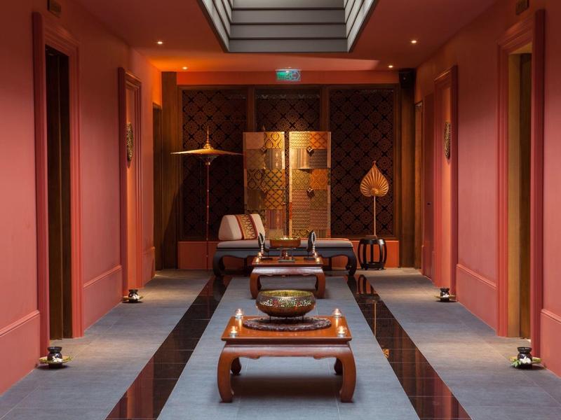 Stylowo urządzony korytarz hotelowy z ciepłym oświetleniem i tradycyjnymi meblami.