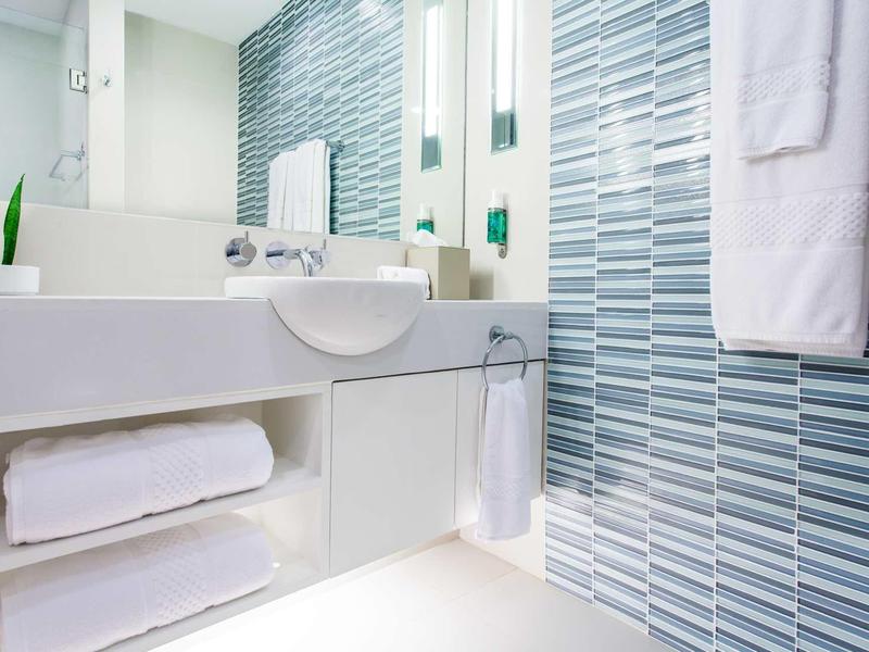 Modern bathroom with white fixtures and blue tiled walls.
