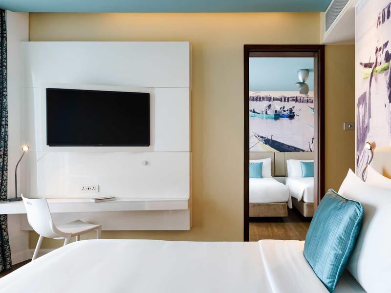 Modern hotel room with TV, desk, and cozy bed with pillows.