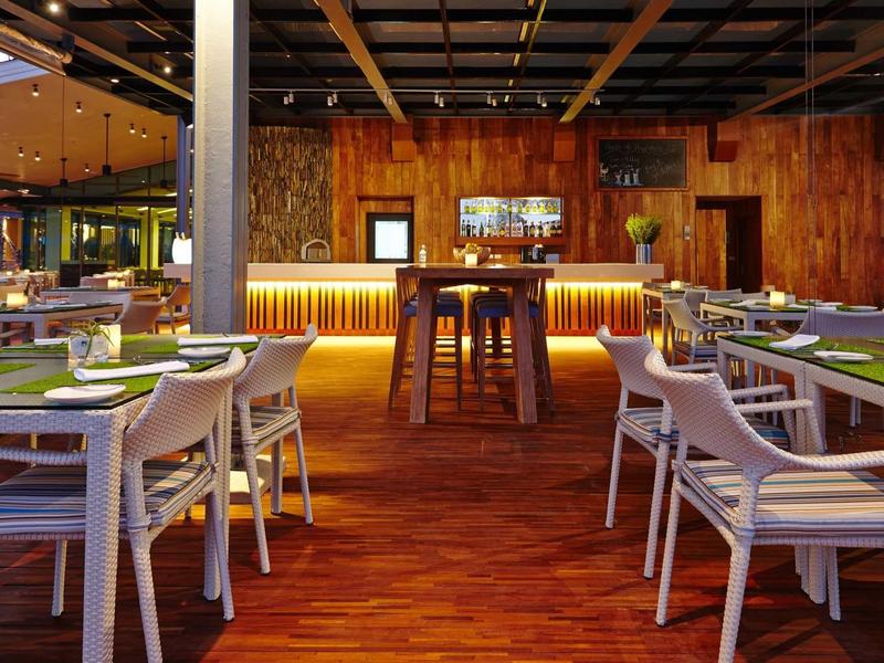 Modern restaurant with wooden floor, white chairs, and illuminated bar counter