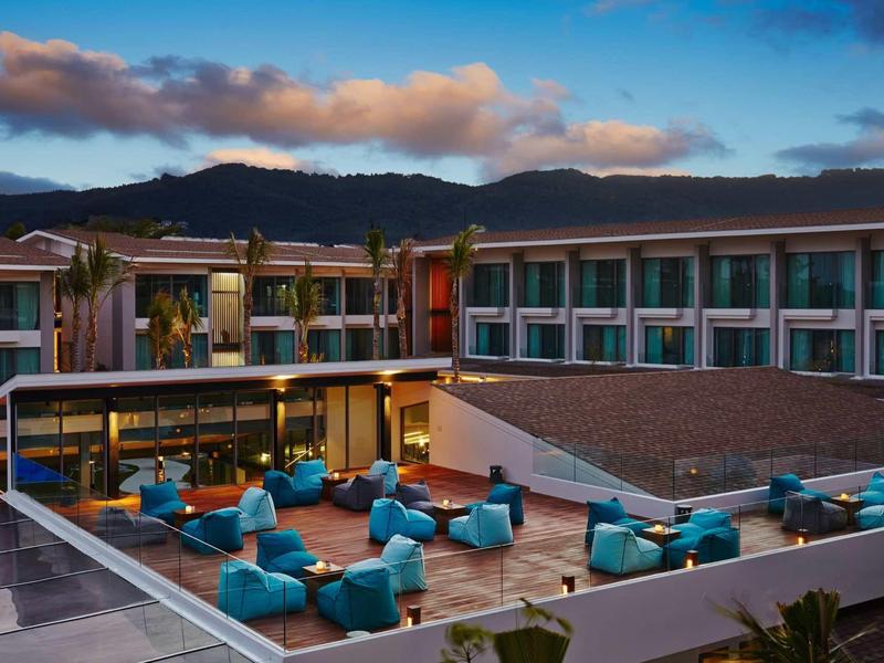 Modern hotel courtyard with blue bean bags and palm trees at sunset.