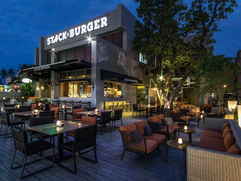 Cozy outdoor terrace of a burger restaurant in the evening with seating and lighting.