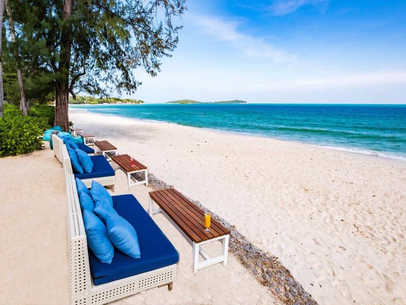 Beach with sun terrace, blue cushions, and sea view under clear sky.