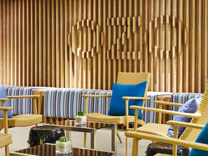 Modern lounge with wooden paneling and colorful cushions in a hotel interior.