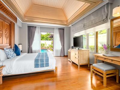 Jasny pokój hotelowy z podwójnym łóżkiem, dużym oknem i drewnianą podłogą