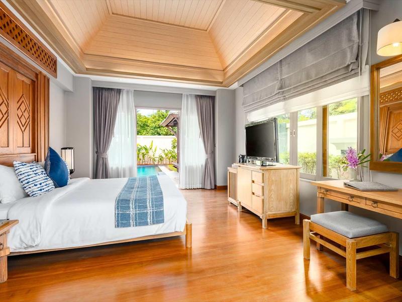 Jasny pokój hotelowy z podwójnym łóżkiem, dużym oknem i drewnianą podłogą