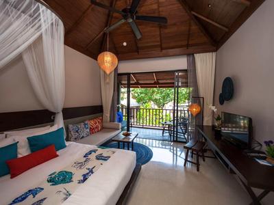 Gemütliches Schlafzimmer mit Holzdach, großem Bett, Balkon und Blick ins Grüne bei Tageslicht.