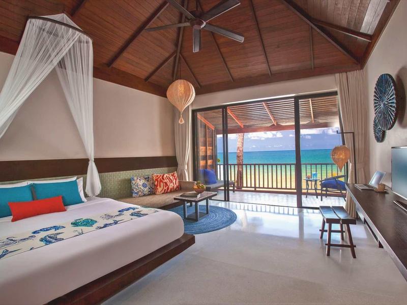 Geräumiges Schlafzimmer mit Holzdecke, Doppelbett, Balkon und Blick auf Meer und Strand.