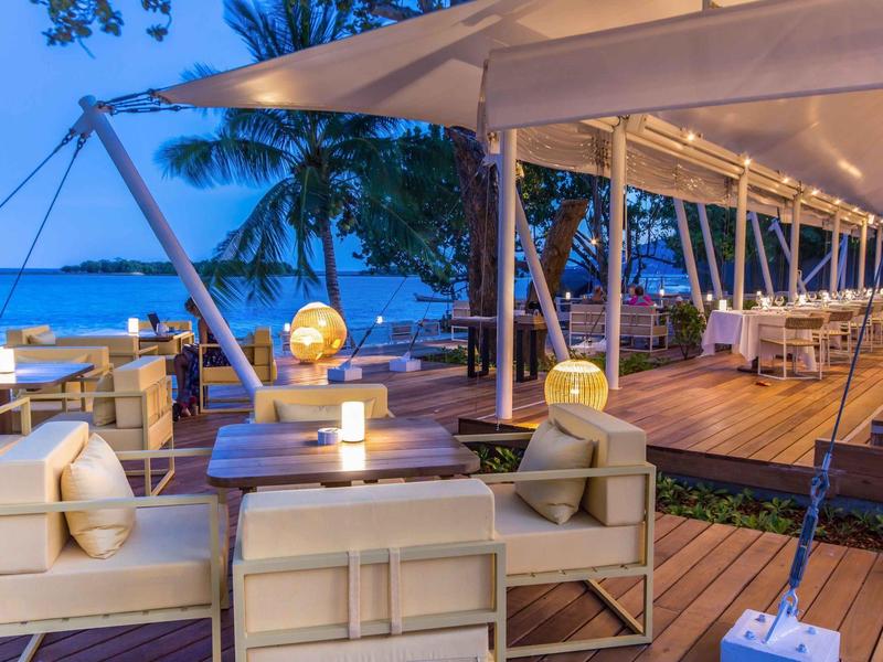 Accogliente area lounge all'aperto con illuminazione e vista mare al crepuscolo.