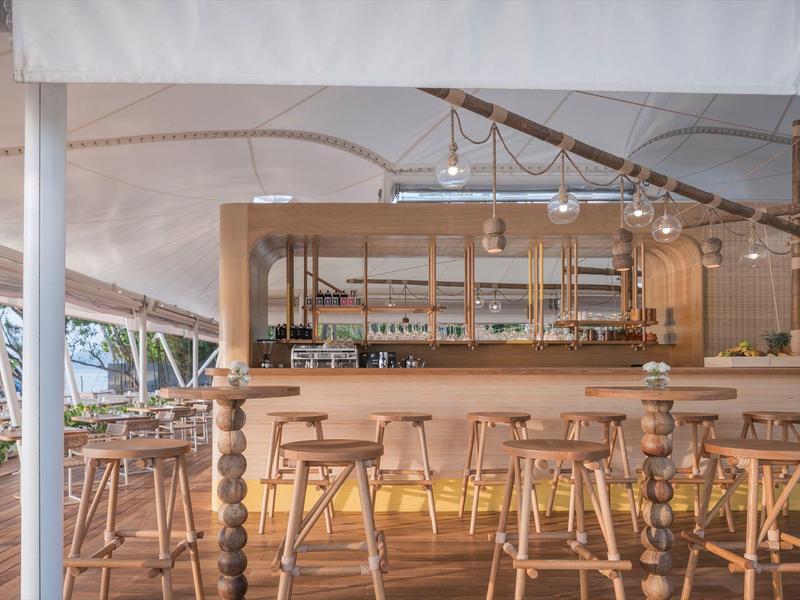 Bar luminosa con sgabelli di legno e luci moderne in uno spazio aperto e arioso con vista sulla natura