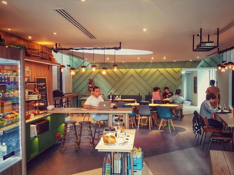 Café moderno con clientes, máquina de bebidas y asientos acogedores para viajeros.