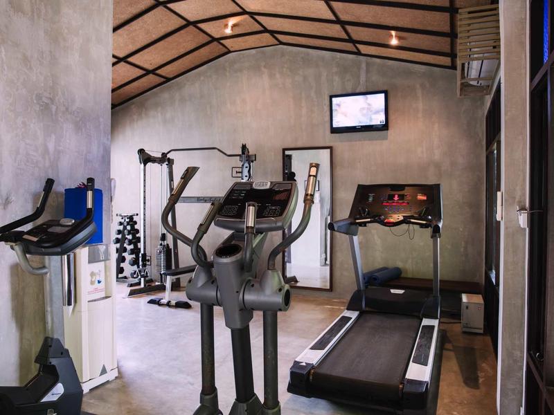 Brightly lit gym with treadmill, elliptical trainer, and dumbbells in a modern design.