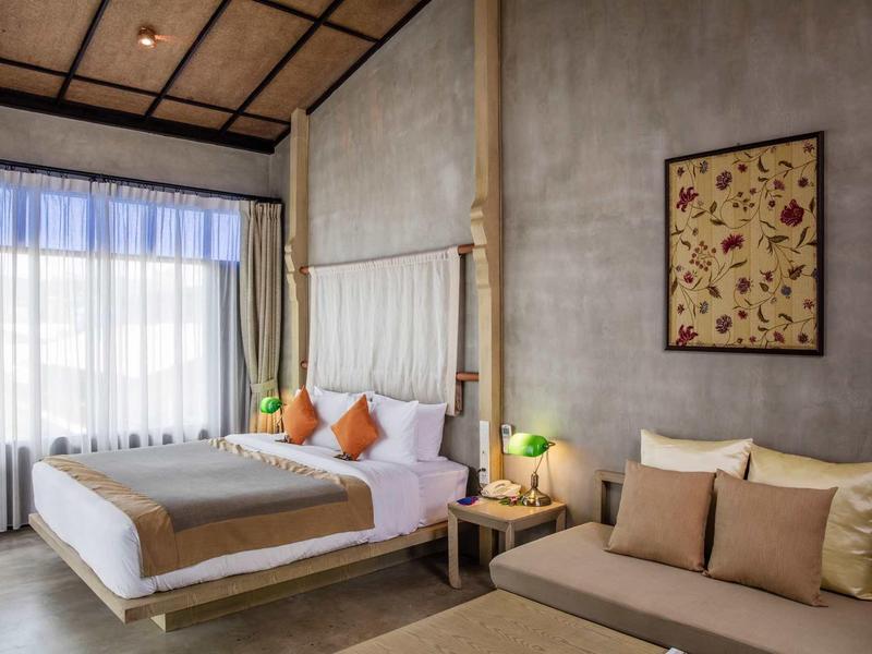 Modern hotel room with double bed, sofa, and large window with curtains.