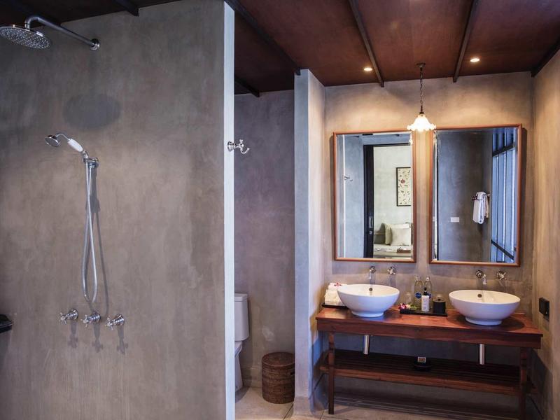 Modern hotel bathroom area with shower, double sinks, and wooden surfaces.
