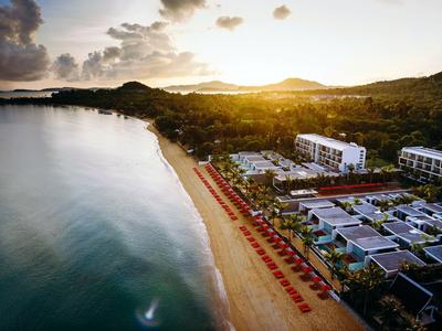 Strandresort mit Sonnenuntergang, roten Sonnenschirmen und ruhigem Meer