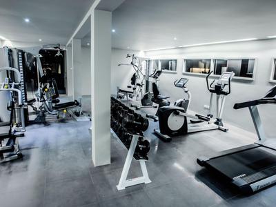 Palestra luminosa con attrezzature moderne come tapis roulant, ellittica e manubri.