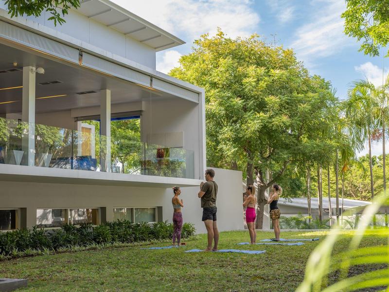 Famiglia che gioca a palla vicino a una casa moderna con giardino durante il giorno.