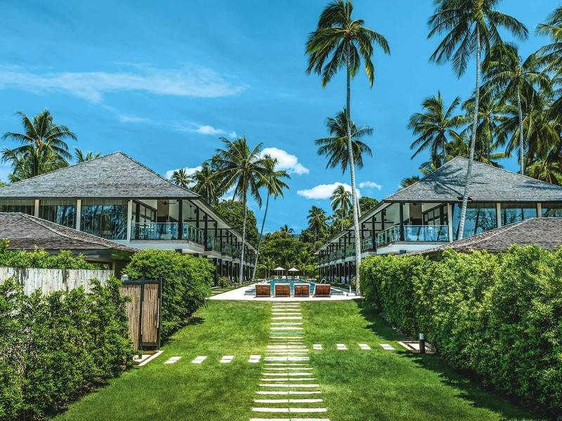 Luxe hotelresort met palmbomen, verzorgd gras en heldere lucht.