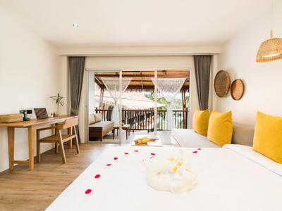 Helles Hotelzimmer mit Gelb akzentuierten Betten, Schreibtisch und Balkon mit Blick ins Grüne.