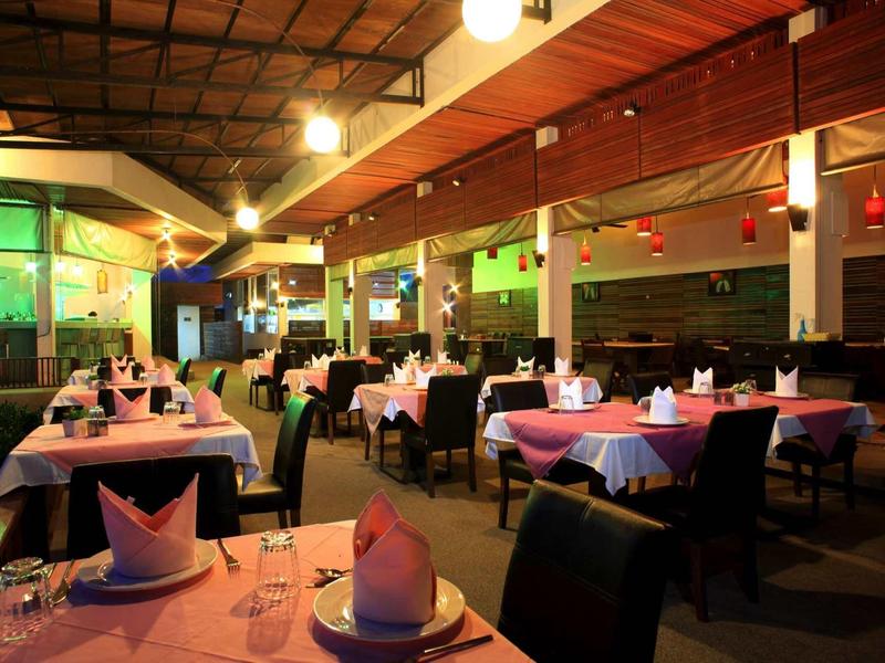 Przytulna restauracja z nakrytymi stołami i przyciemnionym oświetleniem tworzącym miękką atmosferę.