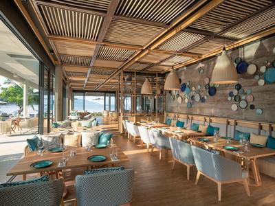 Moderní restaurace s dřevěným interiérem a výhledem na venkovní terasu.